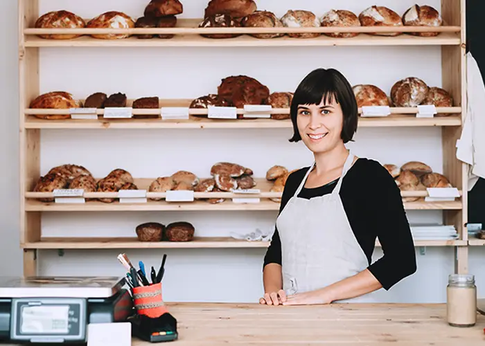 Local SEO | Picture of female baker standing in front of a stand filled with different types of bread - Juan Rojo Design Toronto