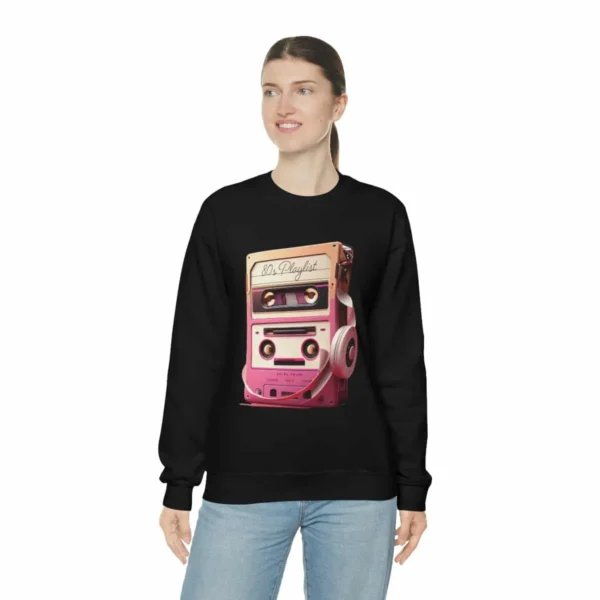 80s Playlist Sweatshirt Unisex, 80s retro hoodie, 80s style hoodie, 80s retro hoodie and Gen X | Picture of woman wearing a black sweatshirt with the graphic of a tape player with headphones sitting on top of it and on the tape label the words 80s Playlist have been written - Juan Rojo Design Toronto