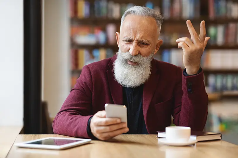 Craft Relevant and Quality Content | Picture of older man clearly annoyed at the email he just received on his mobile phone - Juan Rojo Design Toronto