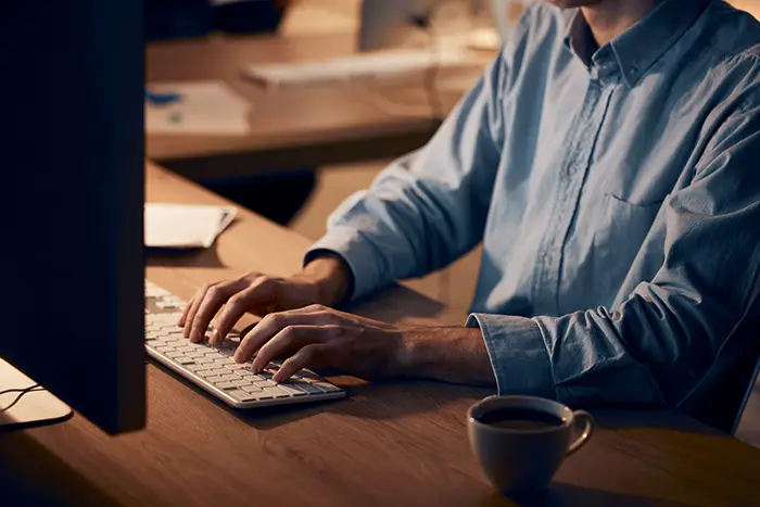 SEO Copywriting | Man typing on a keyboard in a dim lit office - Juan Rojo Design Toronto